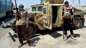 ISIS militants stand with a captured American Humvee, given to the Iraqi Army and captured by ISIS, June 19, 2014. CREDIT: AP 