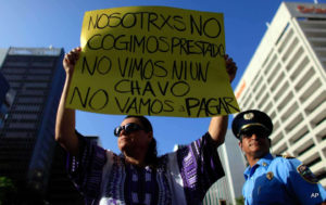 A protester holds a sign that reads in Spanish, “We didn’t take out a loan. We didn’t see a dime. We’re not going to pay” during a protest in San Juan, Puerto Rico, on July 15, 2015.
